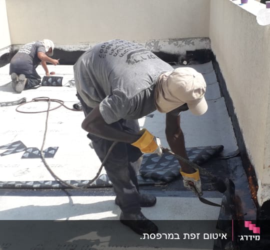 שני עובדים מבצעים איטום גג בעזרת יריעות ביטומניות